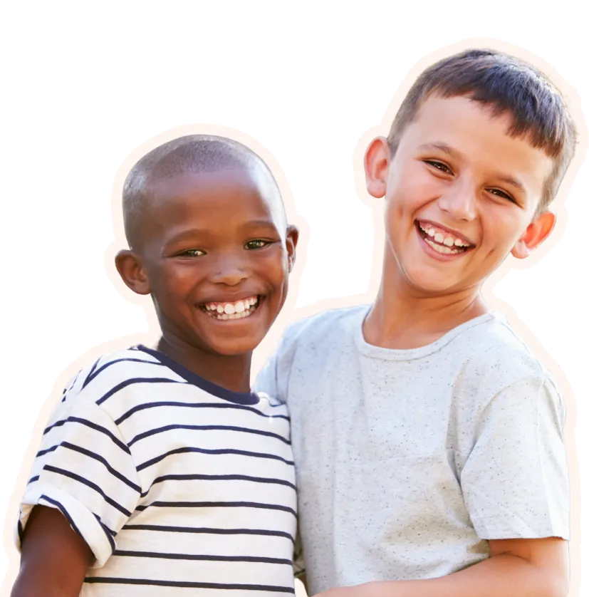 Two young boys stand together smiling at the camera against a white background
